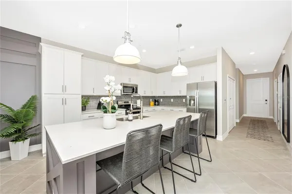 a kitchen with kitchen island a dining table chairs and white cabinets