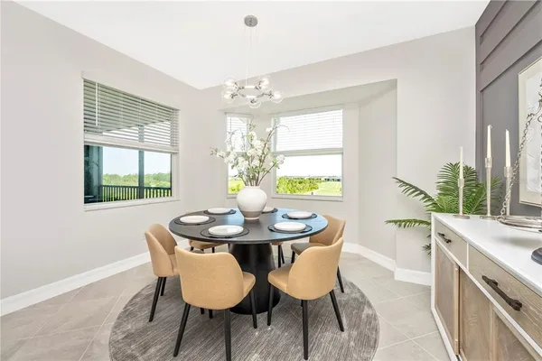 a living room with lots of furniture kitchen view and a large window