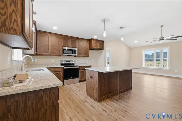 a kitchen with stainless steel appliances kitchen island granite countertop a stove a sink a refrigerator and a microwave