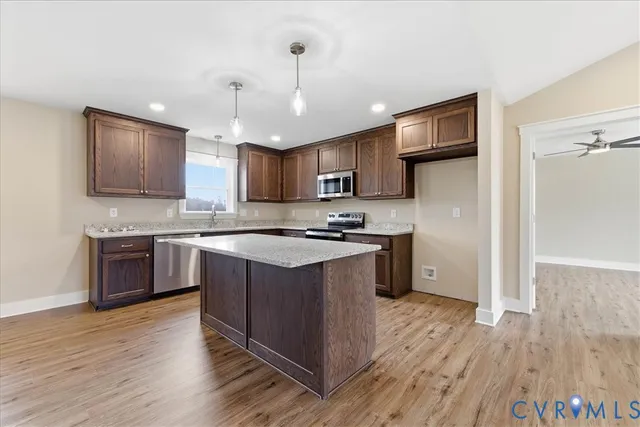 a large kitchen with stainless steel appliances granite countertop a stove a sink dishwasher a refrigerator and a oven with wooden floor