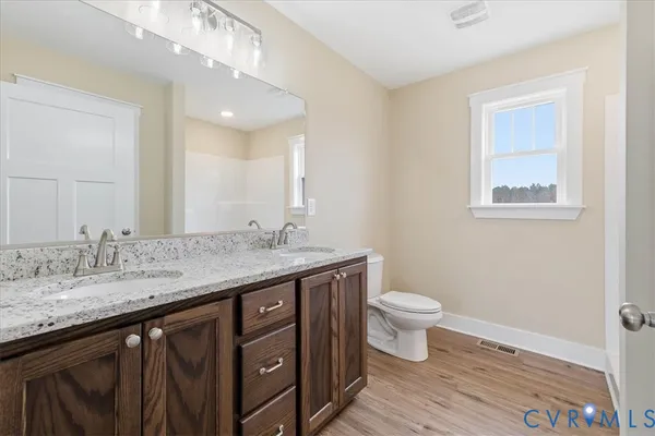 a bathroom with a granite countertop sink a toilet and a mirror