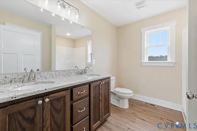 a bathroom with a granite countertop sink a toilet and a mirror