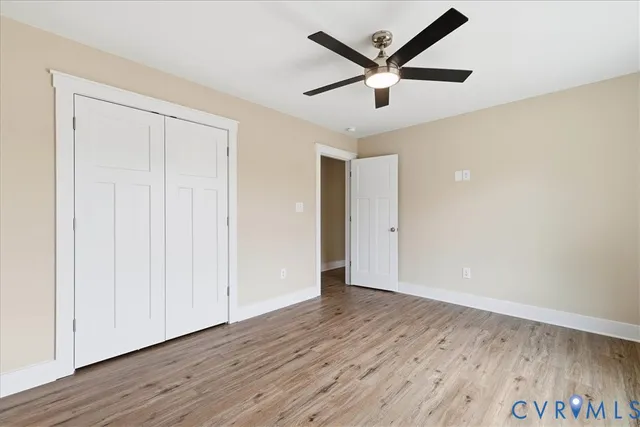 an empty room with wooden floor and a ceiling fan