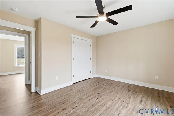 an empty room with wooden floor and a ceiling fan