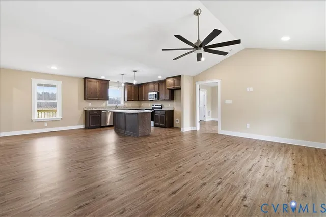 a view of a kitchen with furniture a ceiling fan and wooden floor