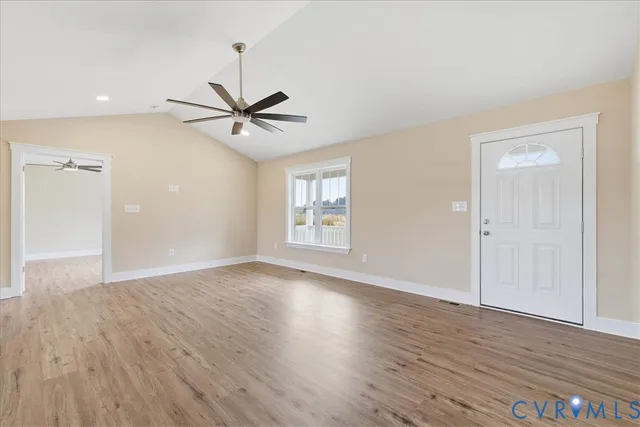 an empty room with wooden floor and a ceiling fan