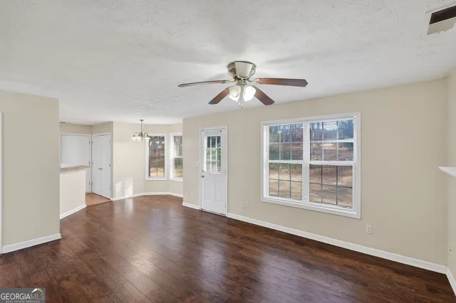 a view of an empty room with a window and wooden floor