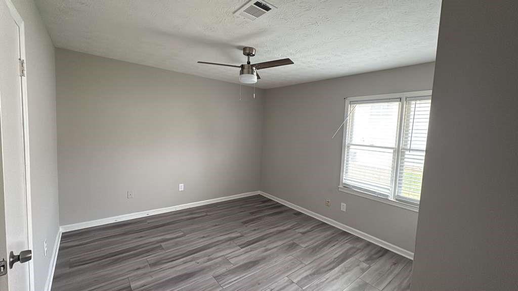 136 Hudson Bridge Terrace Stockbridge, GA 30281 - Photo 5 of 7 an empty room with wooden floor ceiling fan and windows