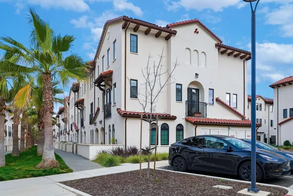 a view of a white building among the street with palm trees