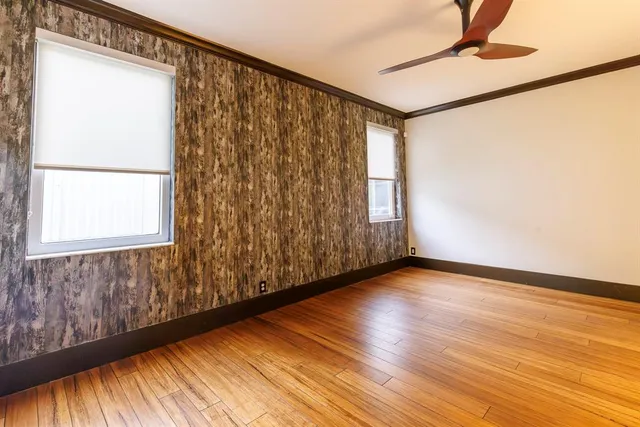an empty room with wooden floor and windows
