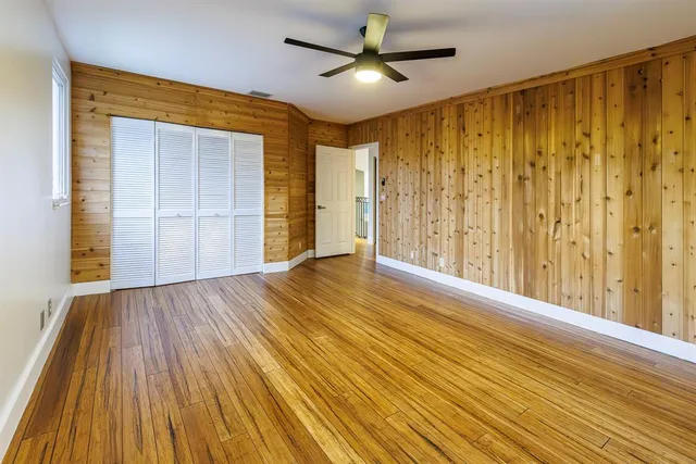 a view of empty room with wooden floor and fan