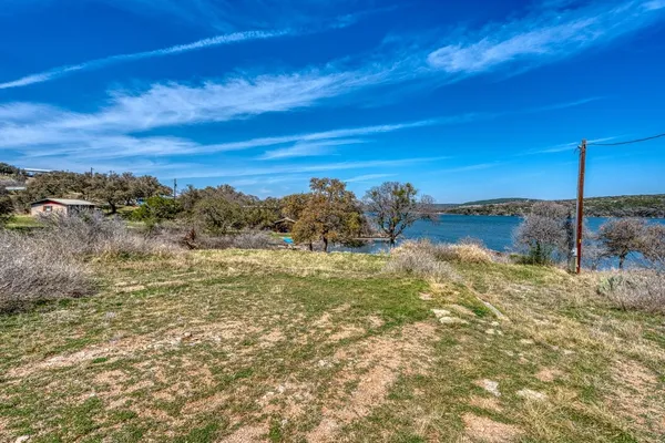 a view of a yard with wooden fence and large trees