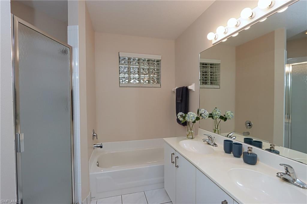 6544 Huntington Lakes Circle, Unit 9204 Naples, FL 34119 - Photo 14 of 31 a bathroom with a tub sink and mirror