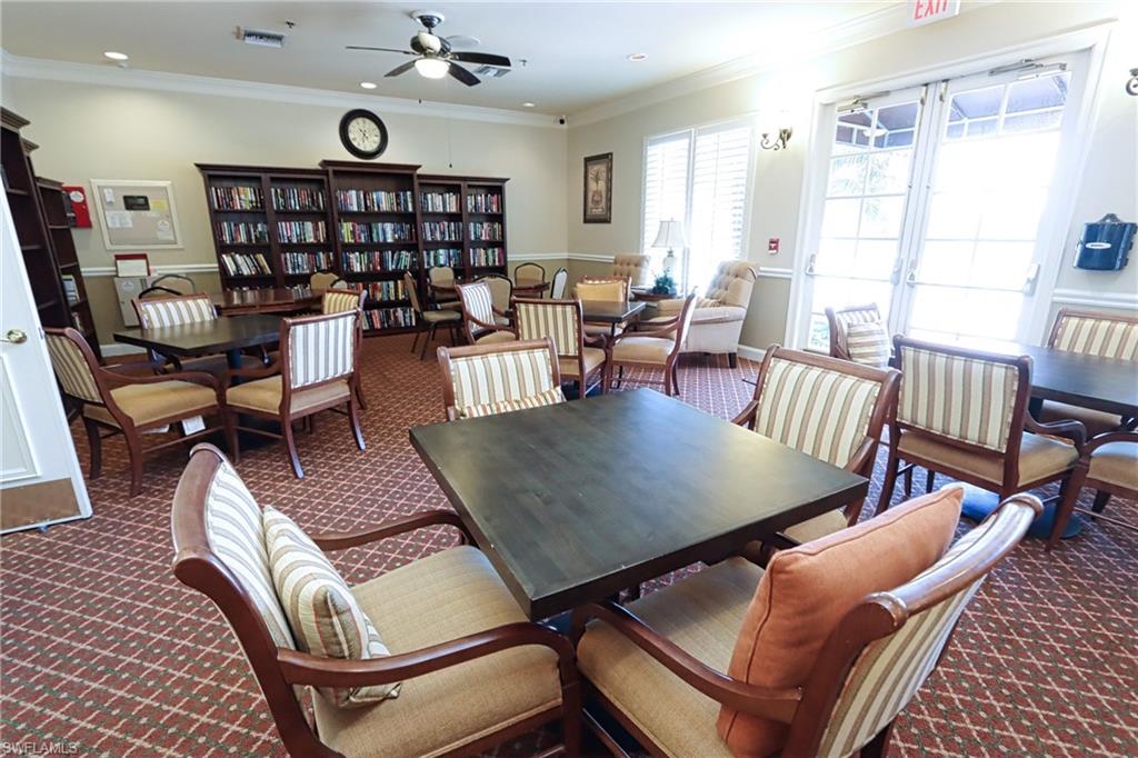 6544 Huntington Lakes Circle, Unit 9204 Naples, FL 34119 - Photo 27 of 31 a living room with furniture a rug and a book shelf