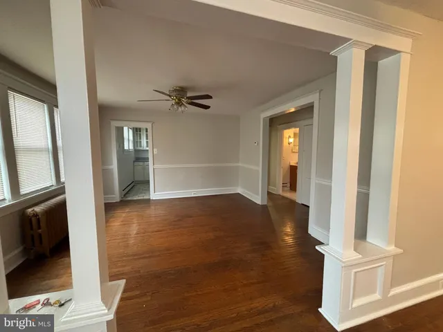 a view of empty room with wooden floor and fan