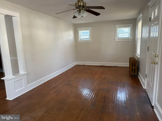 an empty room with wooden floor fan and windows