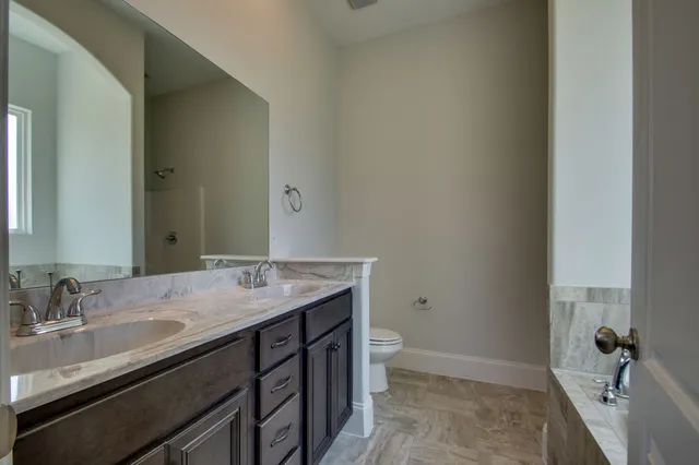 a bathroom with a granite countertop sink a toilet and a mirror