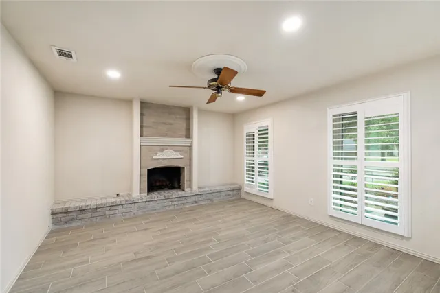 a view of a livingroom with a fireplace a chandelier and windows