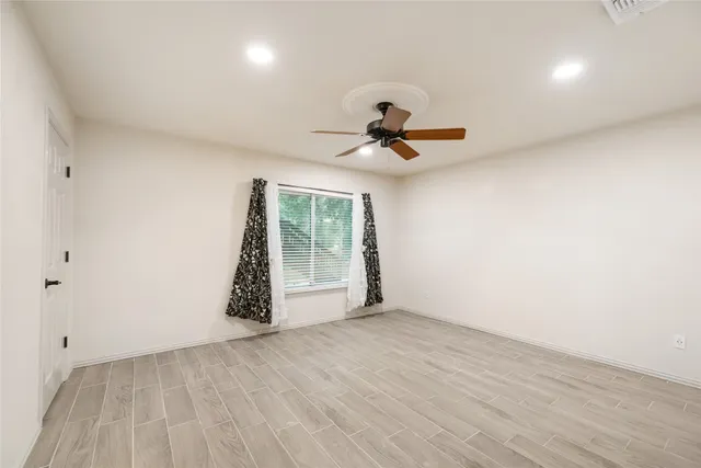 a view of an empty room with a window and wooden floor