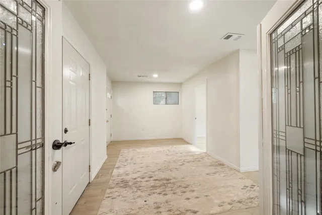 a view of a hallway with wooden floor and a bathroom