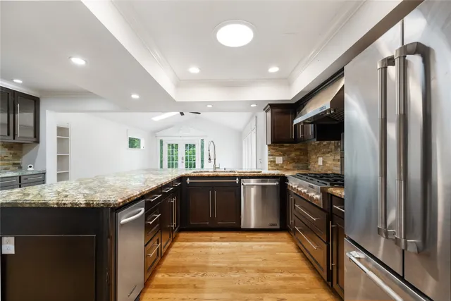 a large kitchen with stainless steel appliances granite countertop a sink stove and refrigerator