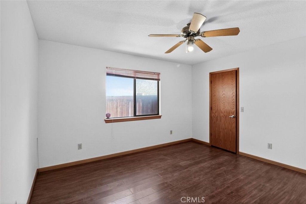 18539 Symeron Road Apple Valley, CA 92307 - Photo 14 of 30 a view of an empty room with wooden floor and a ceiling fan
