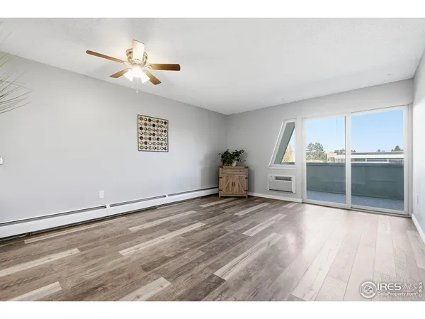 a view of an empty room with a window and wooden floor