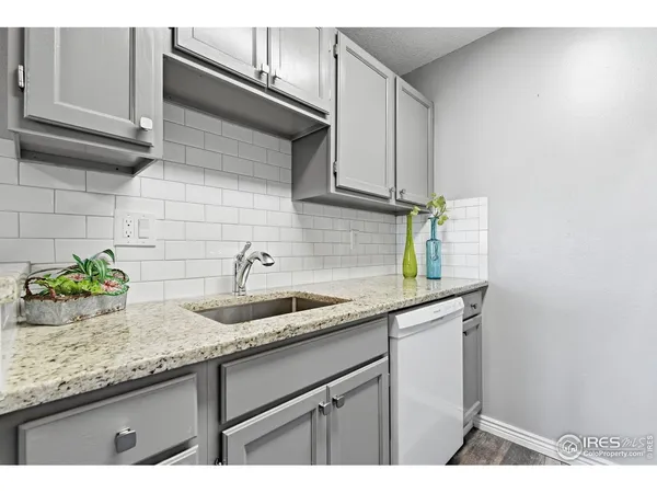 a kitchen with granite countertop a sink and a white cabinets