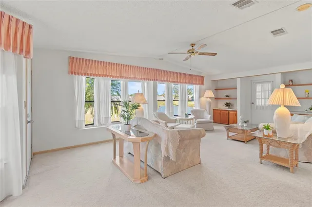 a living room with couches chandelier and a dining table with wooden floor