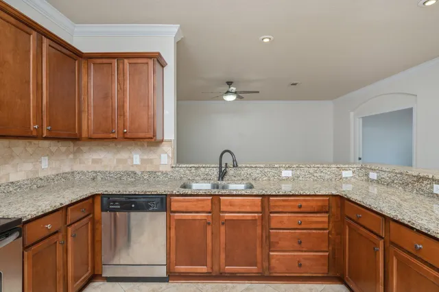 a kitchen with granite countertop a sink cabinets and stainless steel appliances