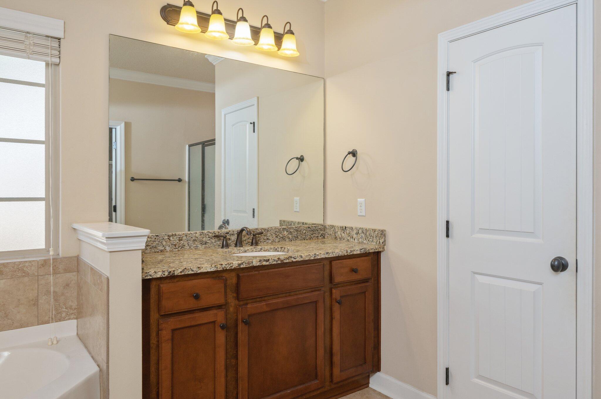 4434 Mirada Way Crestview, FL 32539 - Photo 9 of 42 a bathroom with a granite countertop sink a mirror and a shower