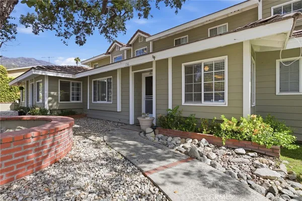 a front view of a house with a yard and potted plants