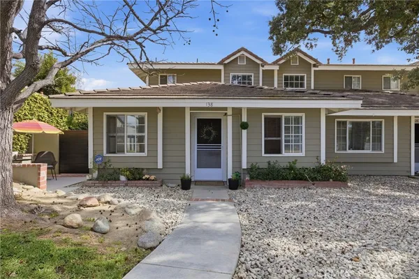 a front view of a house with a yard and potted plants