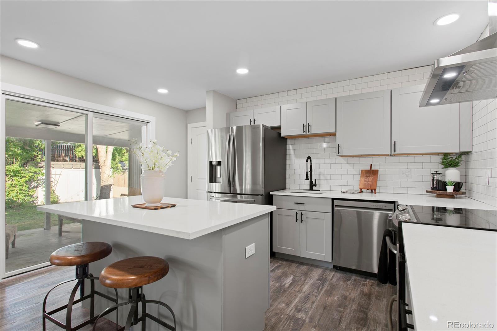 8060 Stuart Place Westminster, CO 80031 - Photo 4 of 18 a kitchen with a stove a sink a refrigerator and white cabinets with wooden floor