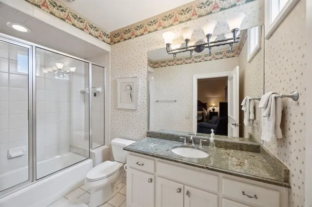 a bathroom with a granite countertop sink a toilet a mirror and shower