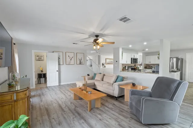 a living room with furniture kitchen view and a chandelier