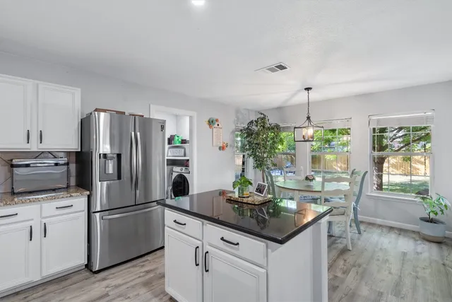 a kitchen with refrigerator and wooden floor