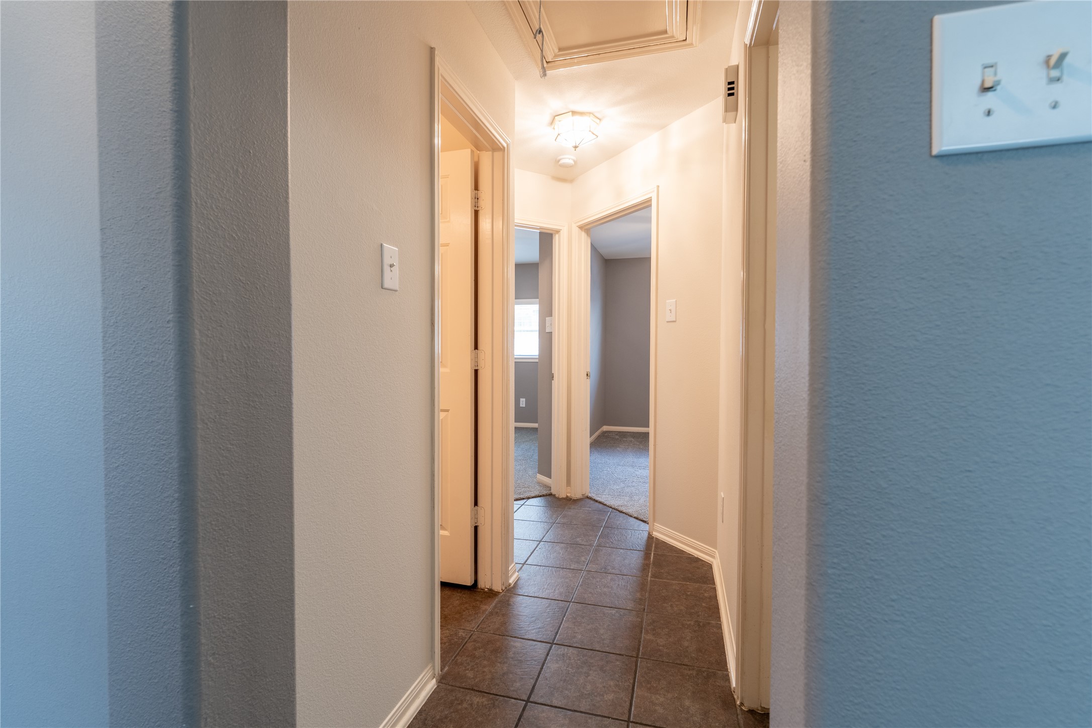10619 Crownsedge Drive Spring, TX 77379 - Photo 19 of 38 A cozy hallway with tiled flooring leading to multiple rooms, featuring soft lighting and neutral walls for a welcoming feel.