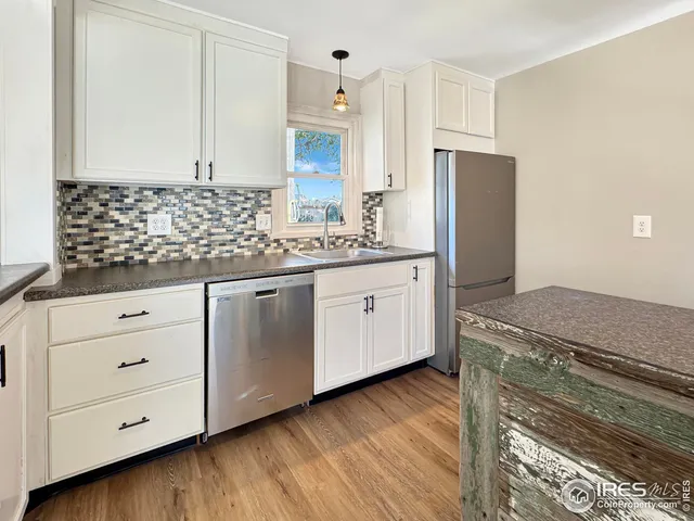 a kitchen with stainless steel appliances granite countertop a sink a stove a refrigerator and cabinets