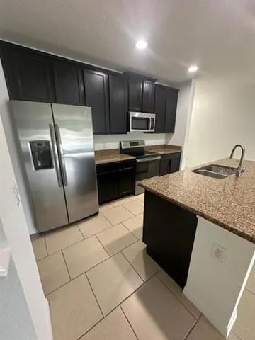 a kitchen with stainless steel appliances granite countertop a refrigerator a sink a stove a microwave and island