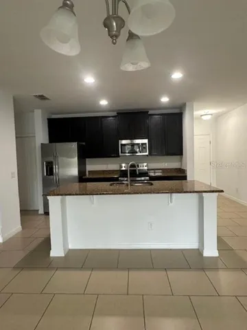 a large kitchen with stainless steel appliances a sink a stove a microwave a counter top space and cabinets
