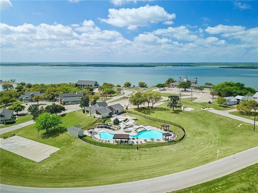 38098 Misty Ridge Drive Whitney, TX 76692 - Photo 2 of 25 Expansive waterfront property featuring multiple residential structures, a large community pool with surrounding lounge areas, and paved roadways