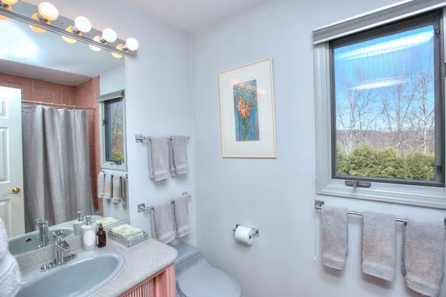 a bathroom with a sink vanity granite toilet and a mirror