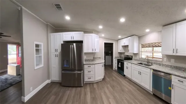 a kitchen with stainless steel appliances granite countertop a refrigerator a stove and a sink