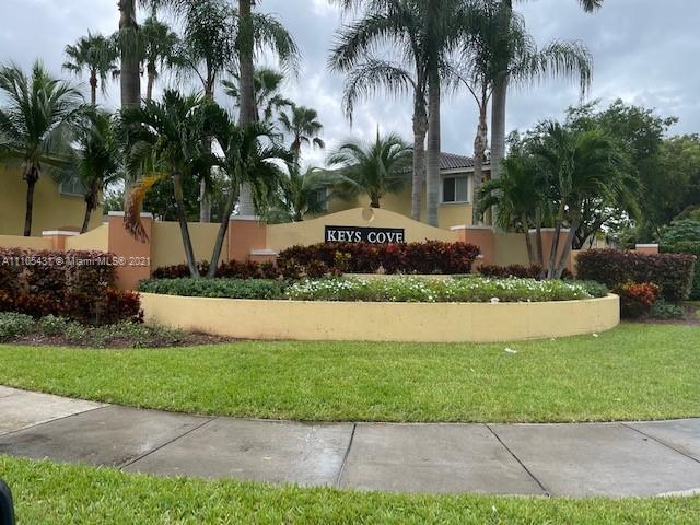 a front view of multi story residential apartment building with yard and sign board
