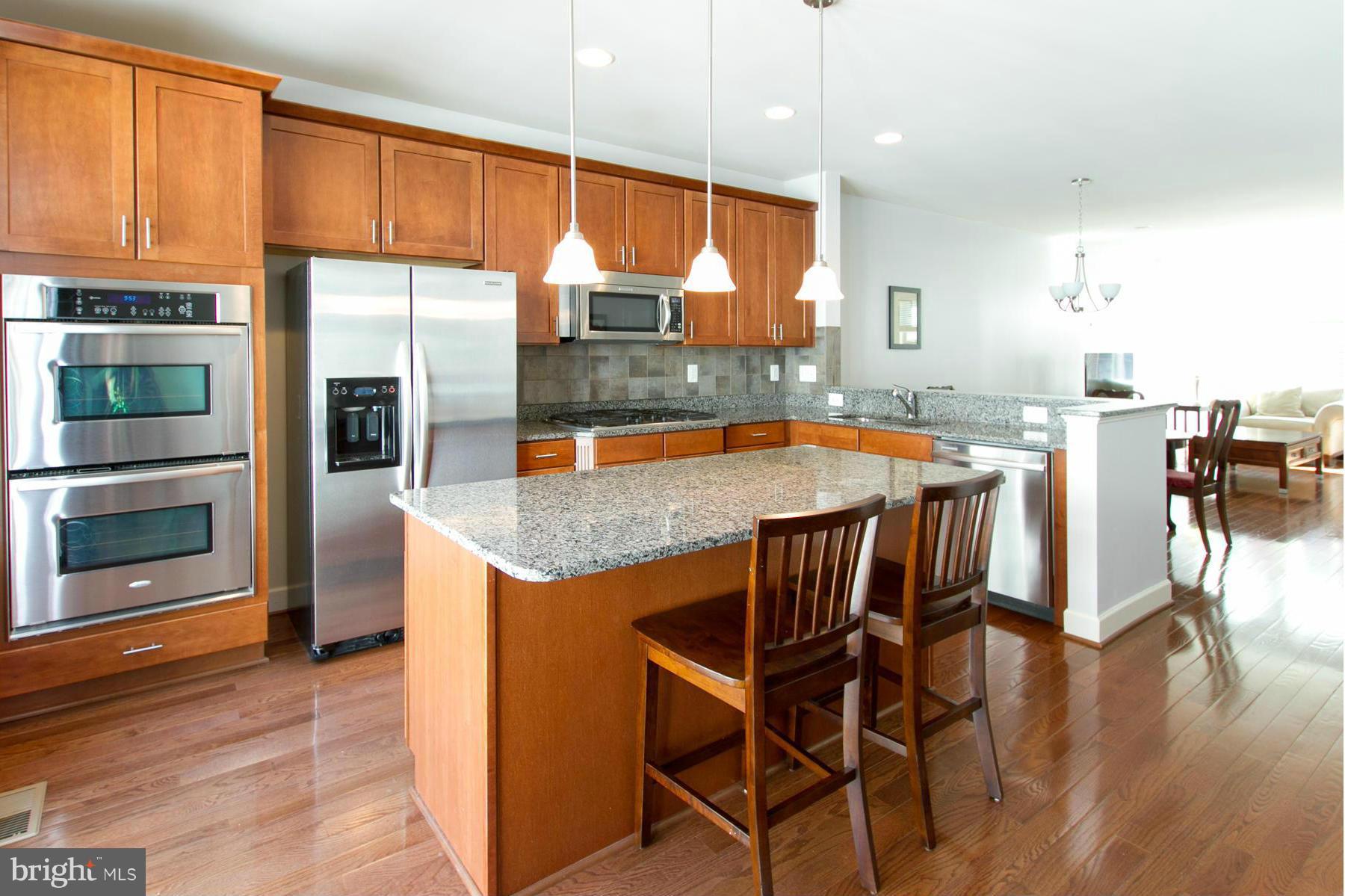 3419 Kemper Road Arlington, VA 22206 - Photo 3 of 30 a kitchen with stainless steel appliances granite countertop a stove top oven a sink a dining table and chairs with wooden floor