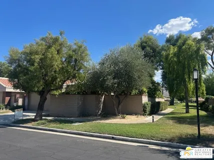 a view of a swimming pool with a yard and palm trees