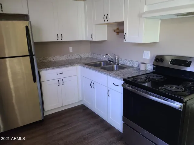 a kitchen with granite countertop a sink stove and refrigerator