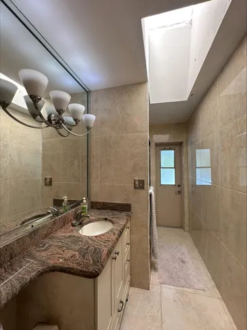a bathroom with a granite countertop sink a mirror and a bathtub