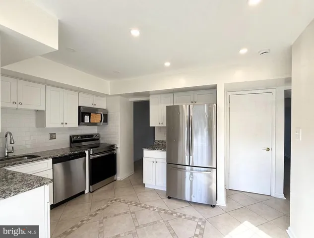 a kitchen with stainless steel appliances granite countertop a refrigerator stove and sink